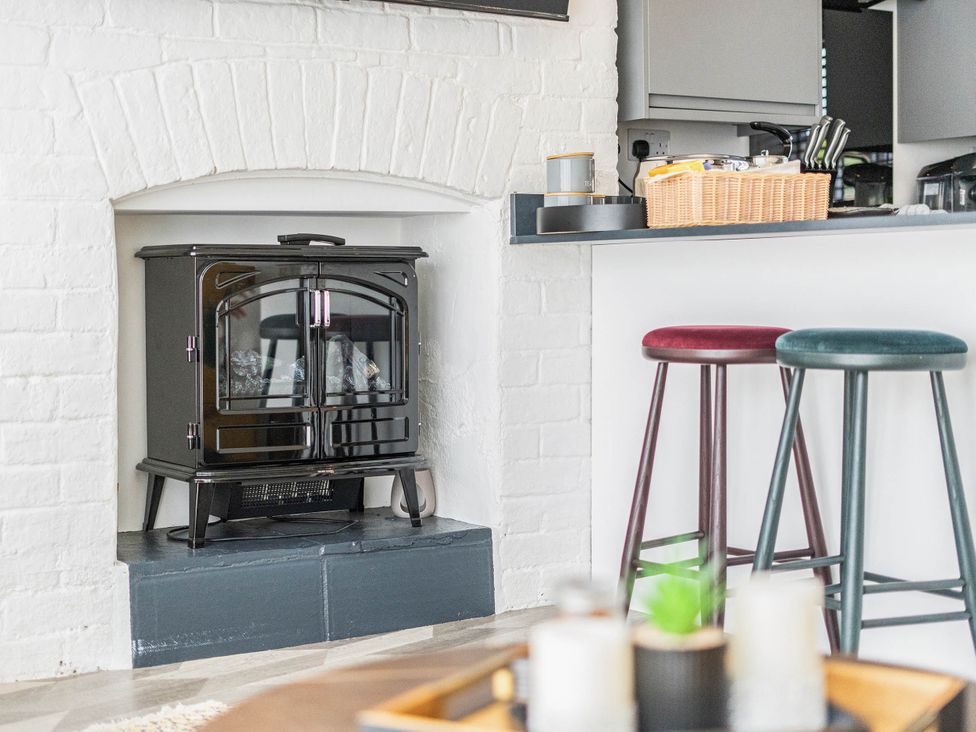 A kitchen with a wood stove and bar stools at Captivating 2 Bed House in Nettleham