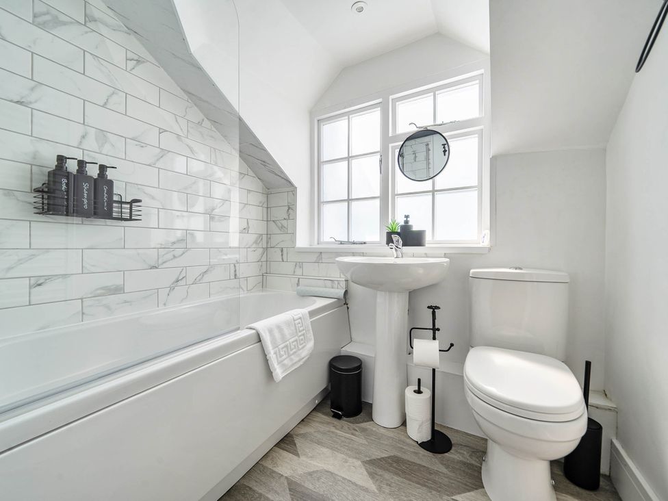 A bathroom with a bathtub, toilet, sink, and windows at Captivating 2 Bed House in Nettleham
