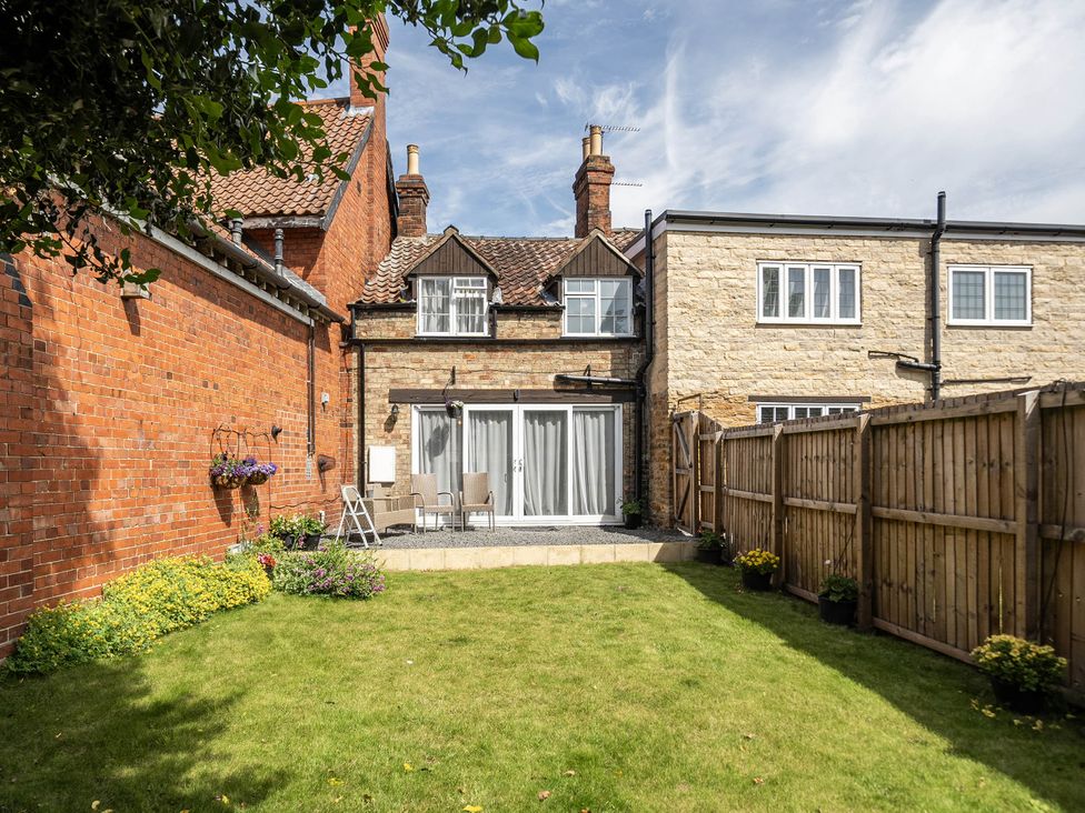 A garden with a house, patio and chairs at Captivating 2 Bed House in Nettleham