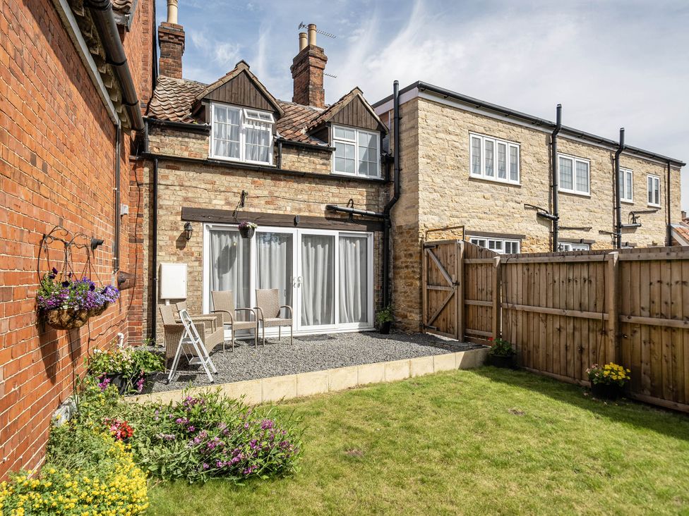 A garden with a sliding door and chairs at Captivating 2 Bed House in Nettleham