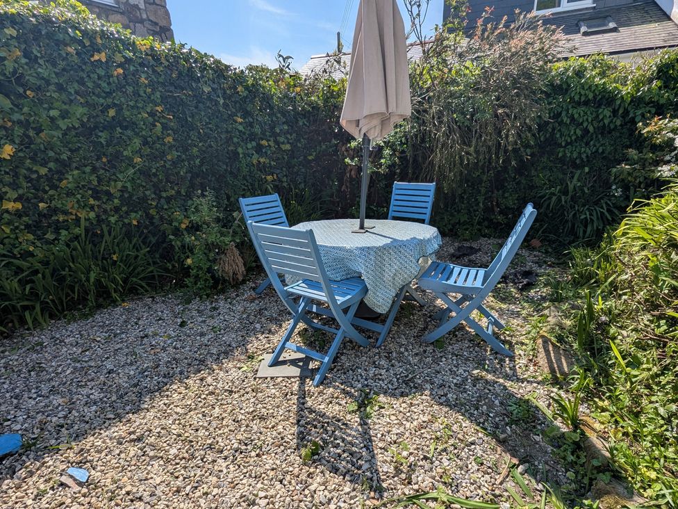 A garden with a table and chairs under an umbrella at The Old Barn near St Ives Rustic Charm Space Lelant