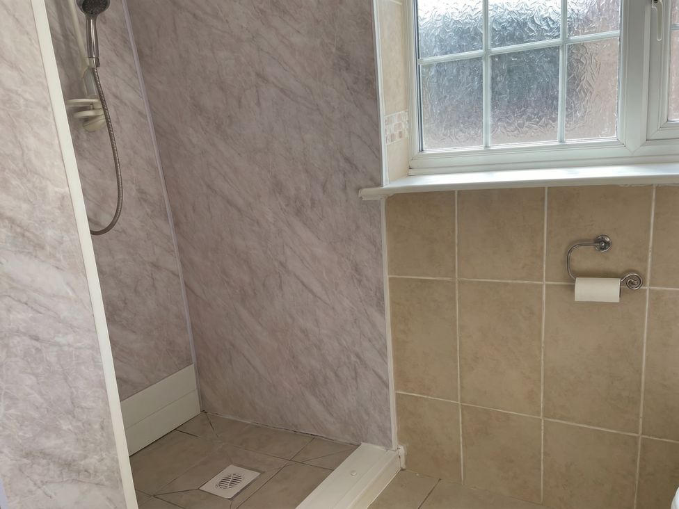 A shower with a window and toilet paper holder at Sweetpea Cottage Sleeps 5 Parking Pets Ok Louth