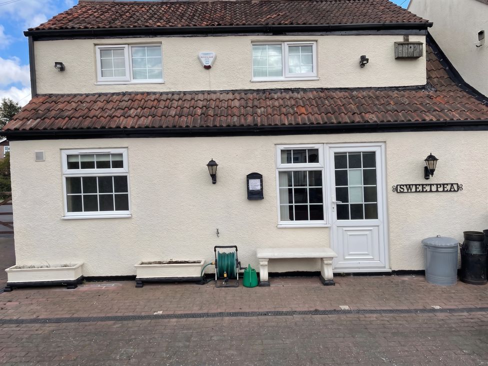 An exterior view of a house with a garden hose and bench at Sweetpea Cottage Sleeps 5 Parking Pets Ok Louth