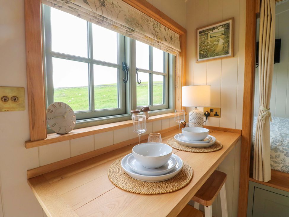 A dining area with a table set for two at Pike House Farm Shepherds Hut 1 Asbourne