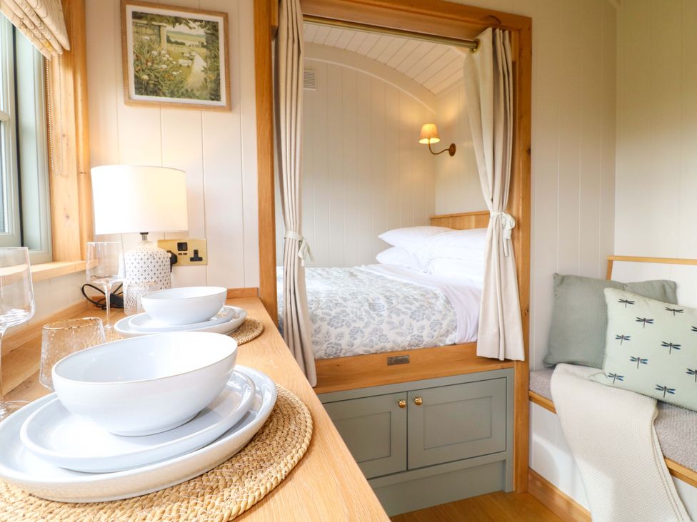 A bedroom with a bed and dining items at Pike House Farm Shepherds Hut 1 in Asbourne