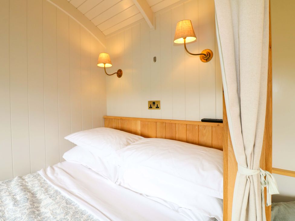 A bedroom with a bed and bedside light at Pike House Farm Shepherds Hut 1 Asbourne