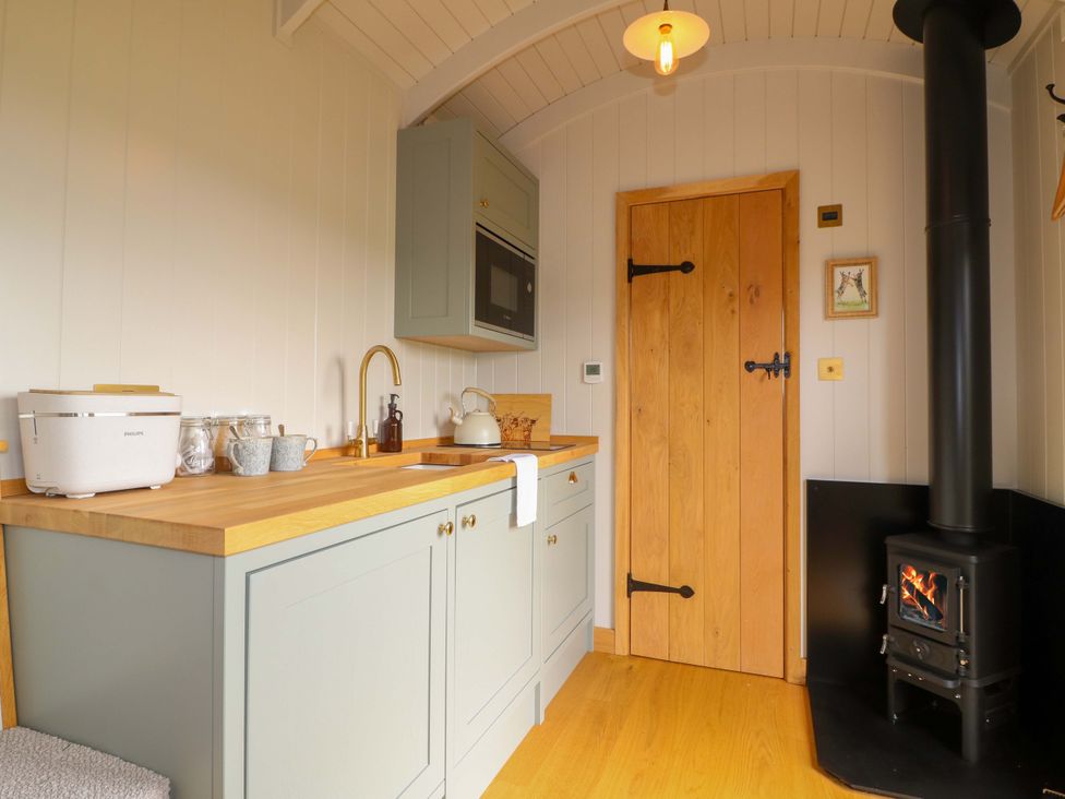 A kitchen with a wooden cabinet and stove at Pike House Farm Shepherds Hut 1 Asbourne