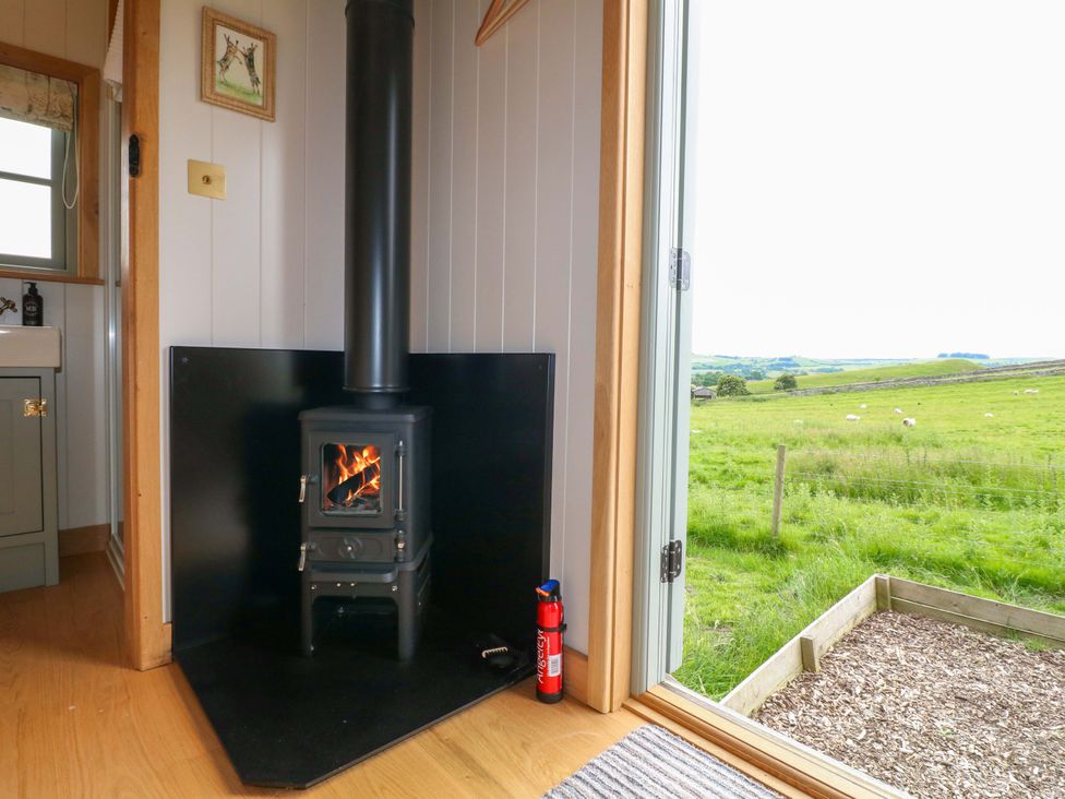 A living room with a wood stove and a window at Pike House Farm Shepherds Hut 1 Asbourne