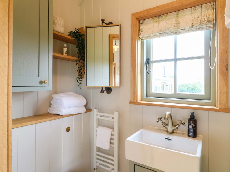 A bathroom with a sink and towels at Pike House Farm Shepherds Hut 1 Asbourne