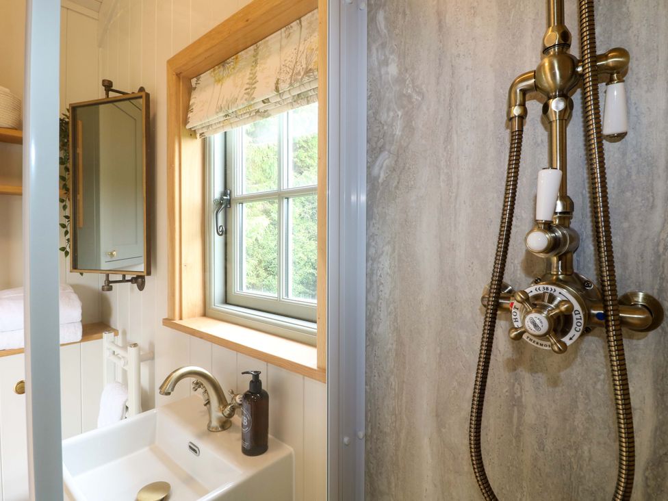 A bathroom with a sink and shower at Pike House Farm Shepherds Hut 1 Asbourne