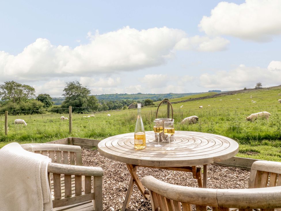 An outdoor area with a table and chairs overlooking a field at Pike House Farm Shepherds Hut 1 Asbourne