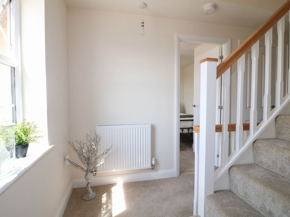 A hallway with a radiator and staircase at No.6 Beck Crescent Ashbourne