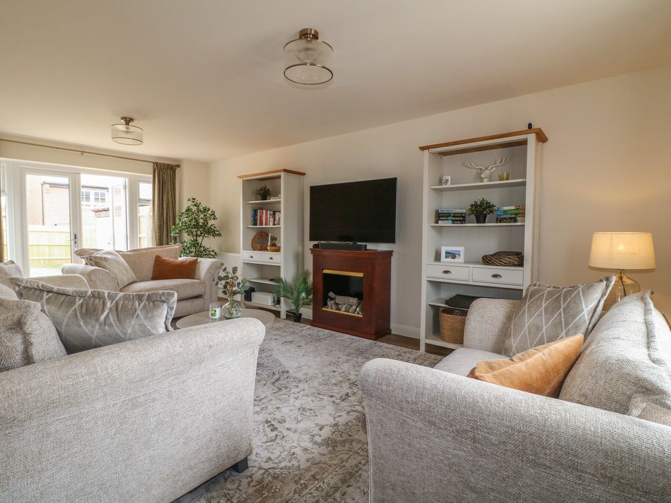 A living room with sofas, a television, and a bookshelf at No.6 Beck Crescent Ashbourne