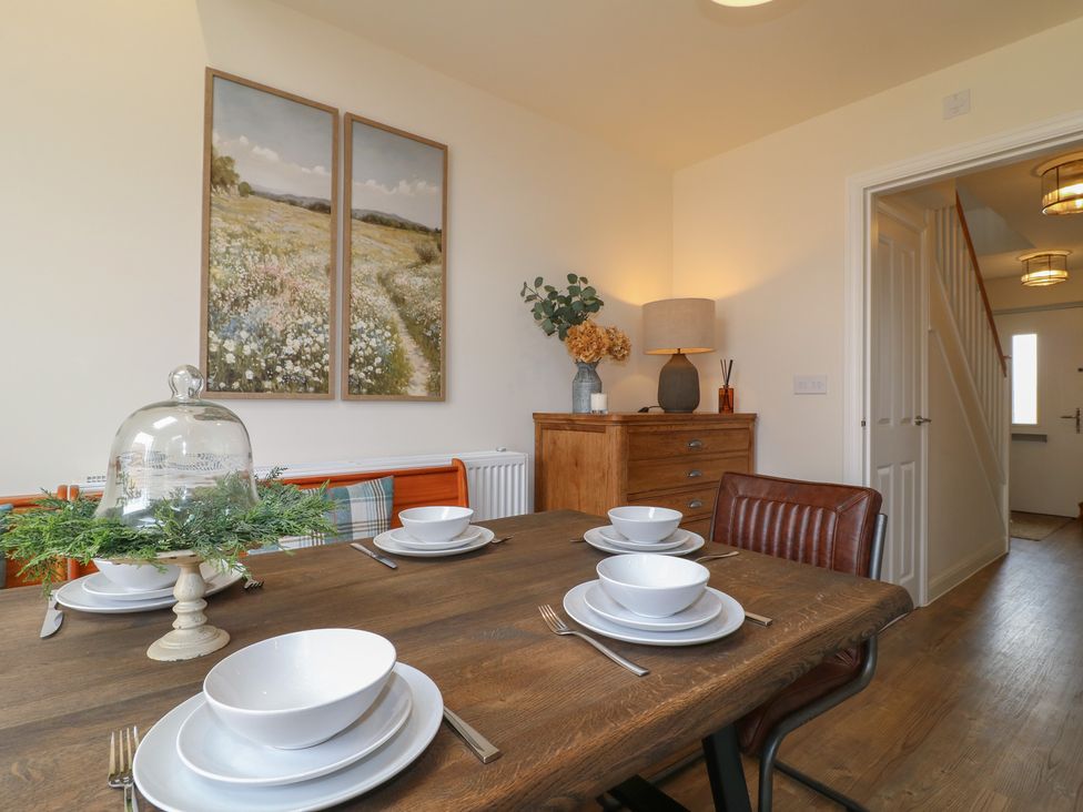 A dining room with a wooden table set for meals at No.6 Beck Crescent in Ashbourne