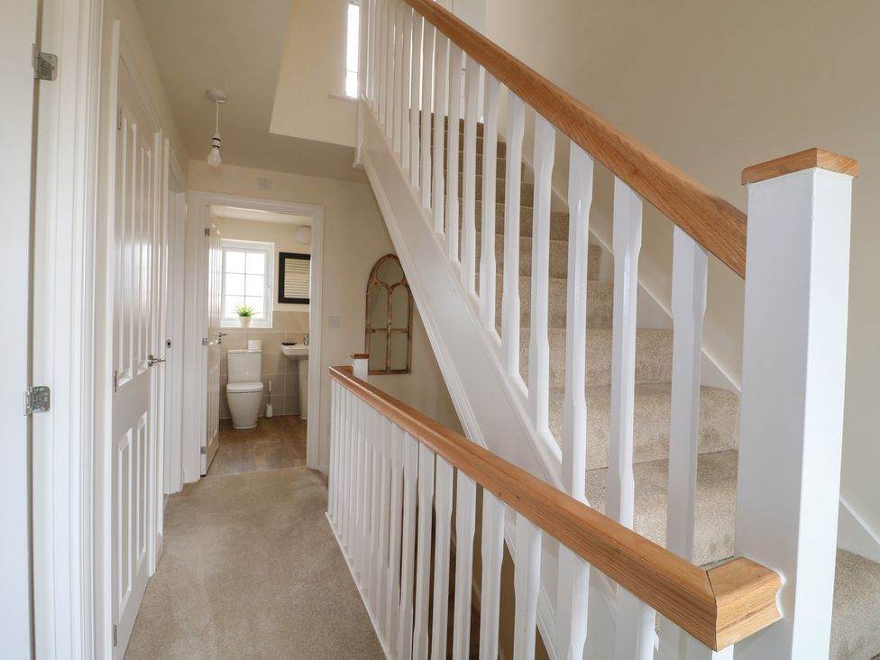 A hallway with a staircase and a toilet at No.6 Beck Crescent in Ashbourne