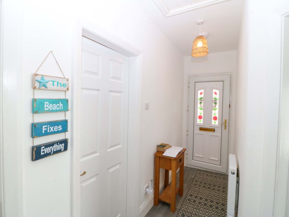 A hallway with a door and a side table at Seaside Bungalow in Rhyl