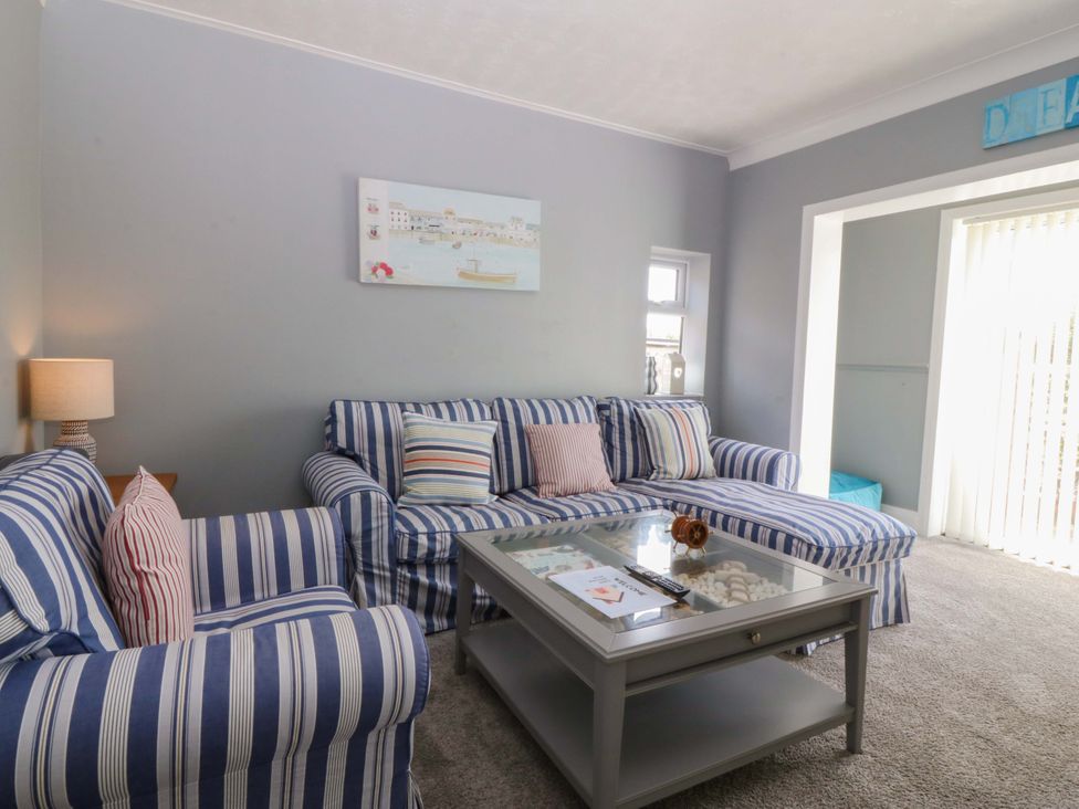 A living room with a striped sofa and coffee table at Seaside Bungalow in Rhyl