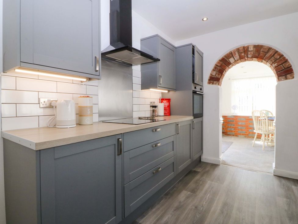 A kitchen with gray units and a bricked archway at Seaside Bungalow in Rhyl