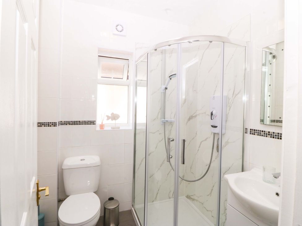 A bathroom with a shower toilet and sink at Seaside Bungalow in Rhyl