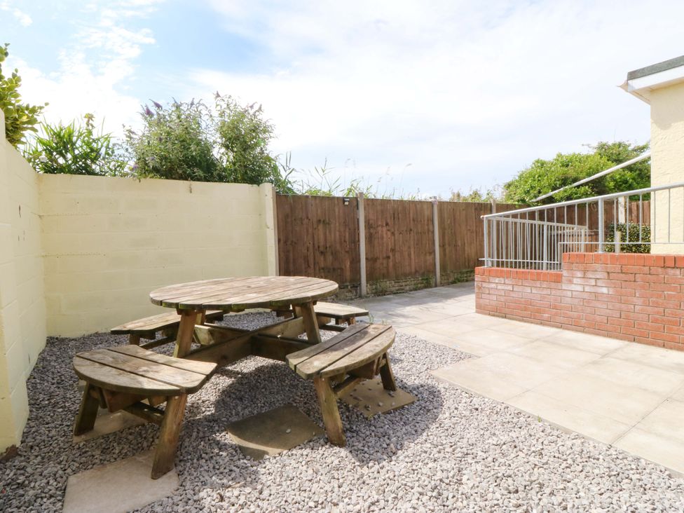 An outdoor seating area with a round table and benches at Seaside Bungalow in Rhyl