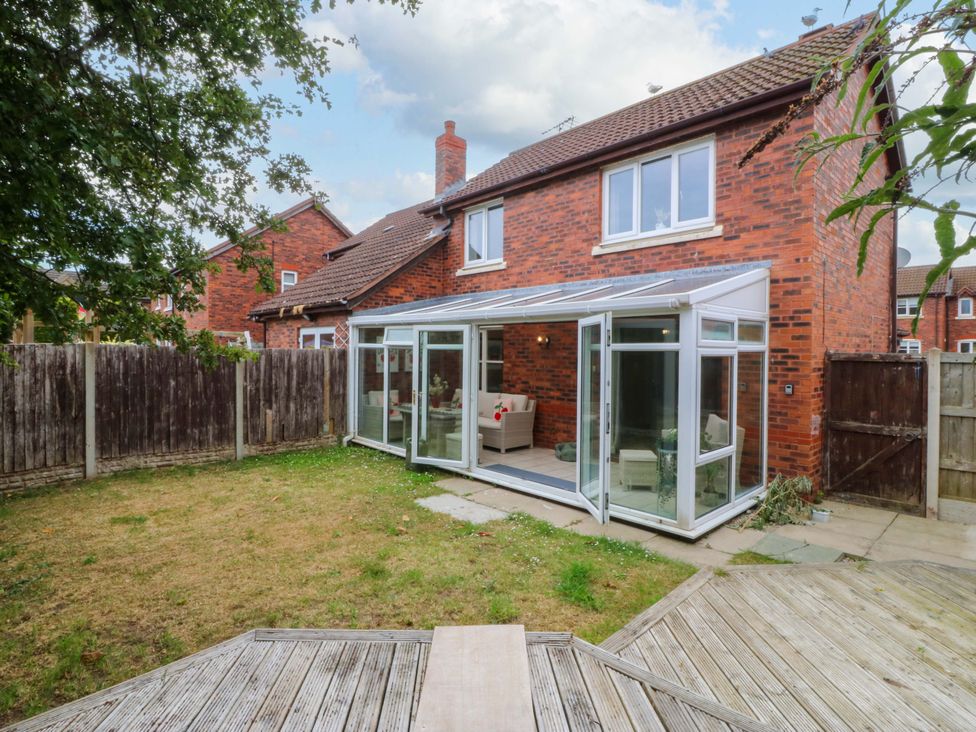 A garden with a conservatory and house at Robins Nest in Rhyl
