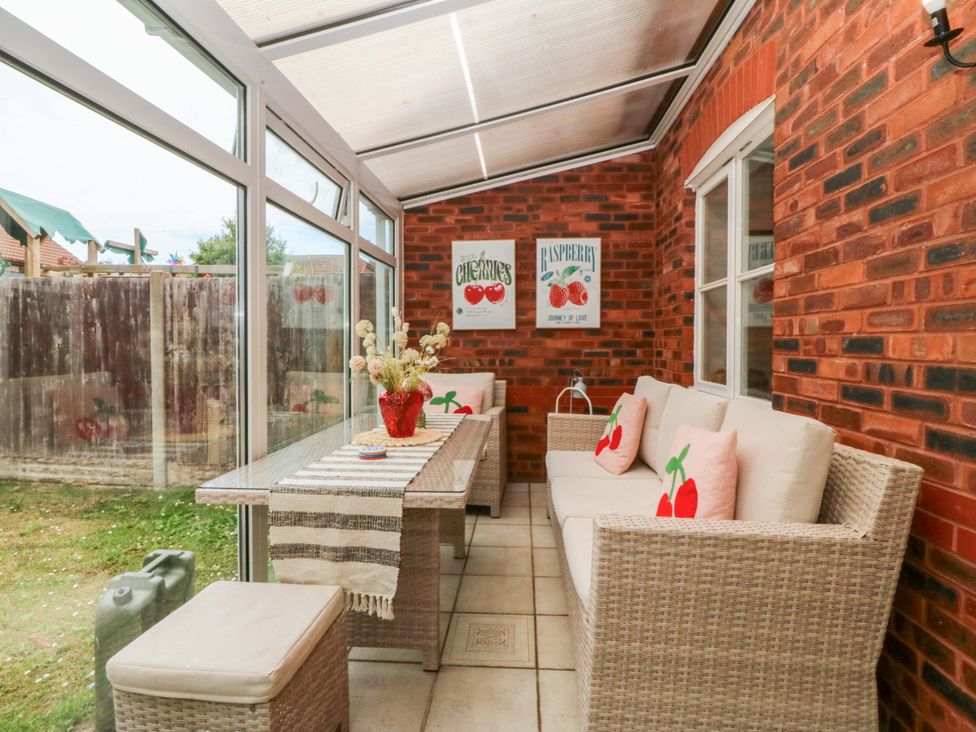 A conservatory with seating arrangement and a dining table at Robins Nest in Rhyl