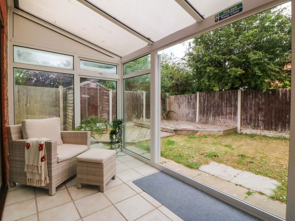 A conservatory with seating area and garden view at Robins Nest in Rhyl