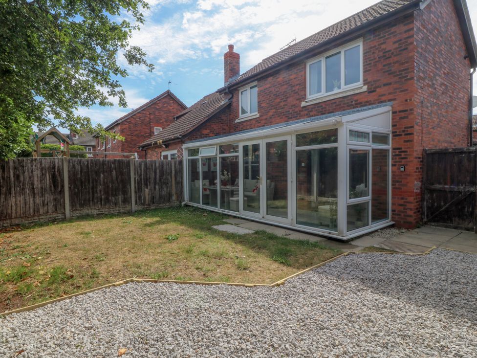 A garden with a conservatory and gravel area at Robins Nest in Rhyl
