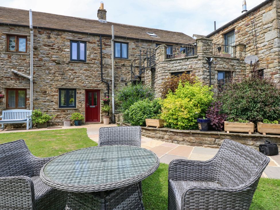 A garden with a table and chairs near a stone house at Kernot Cottage in Reeth