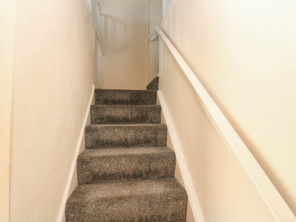 A staircase with carpet and handrail at Kernot Cottage in Reeth