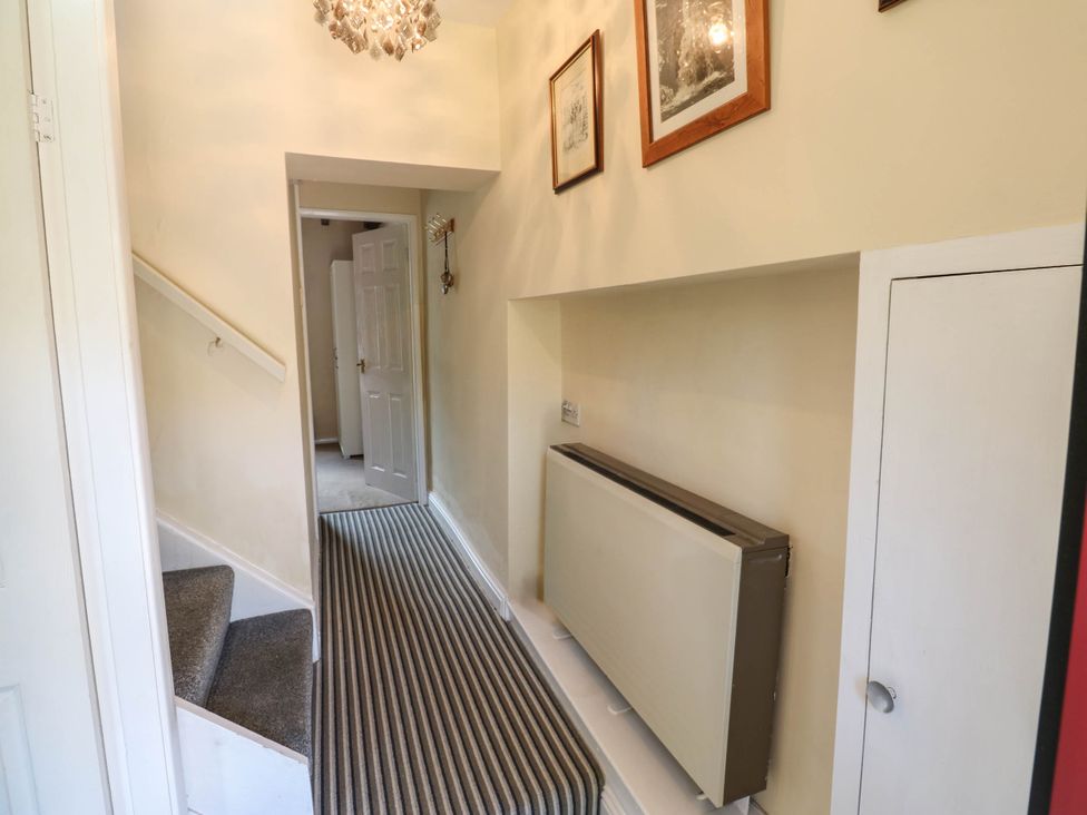A hallway with a staircase and wall heating at Kernot Cottage in Reeth