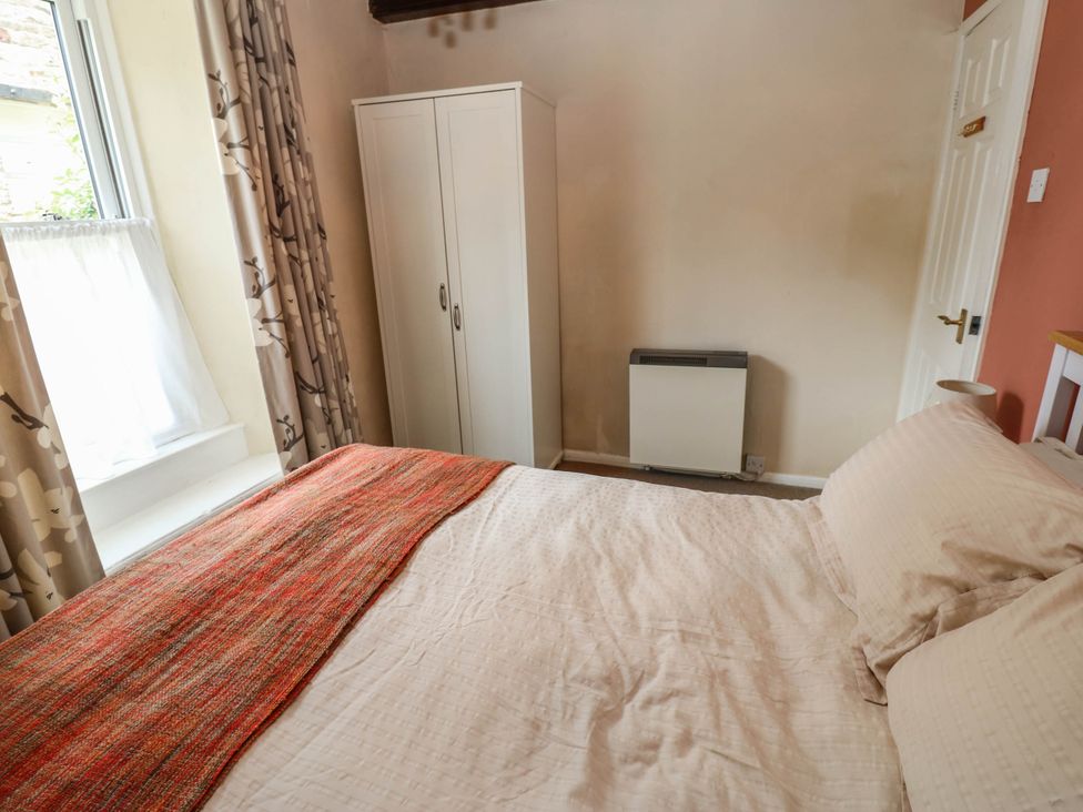 A bedroom with a bed, wardrobe, and radiator at Kernot Cottage in Reeth