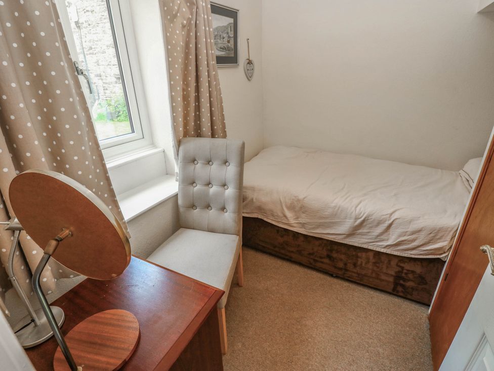 A bedroom with a bed and chair at Kernot Cottage in Reeth