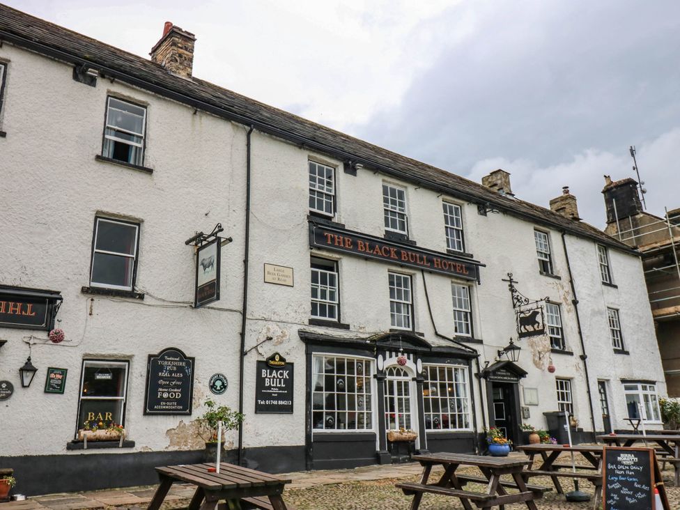 An exterior view of The Black Bull Hotel with tables outside in Reeth