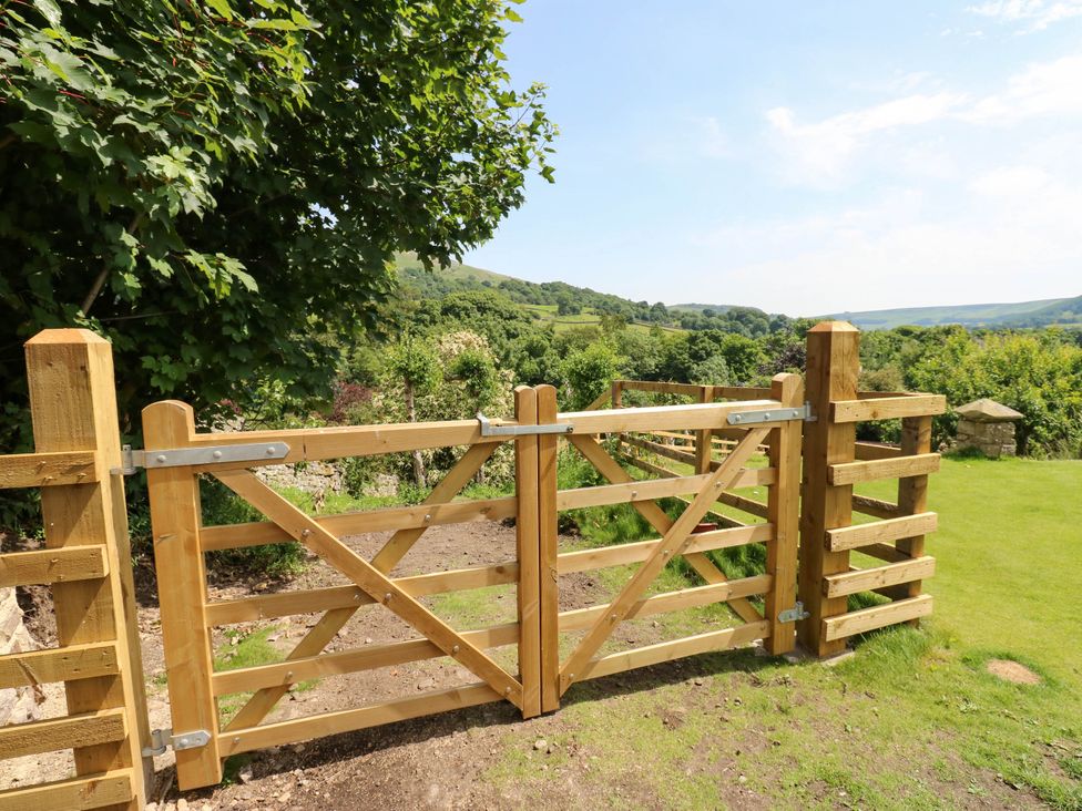 A wooden gate and fence in a grassy area at Kernot Cottage in Reeth