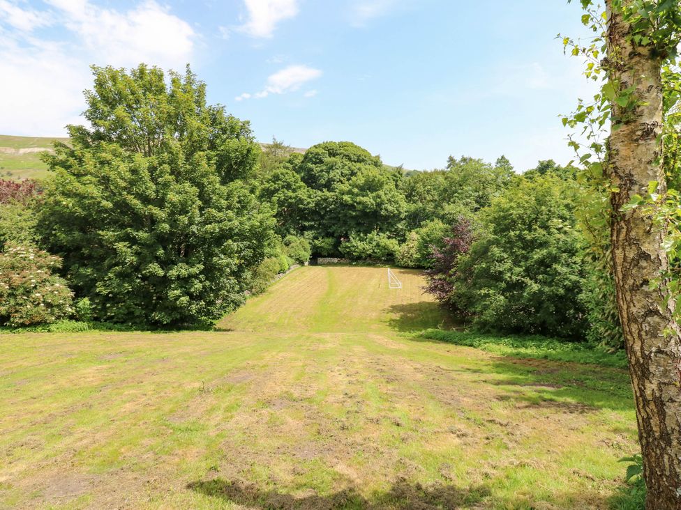 A garden with trees and a grass area at Kernot Cottage in Reeth