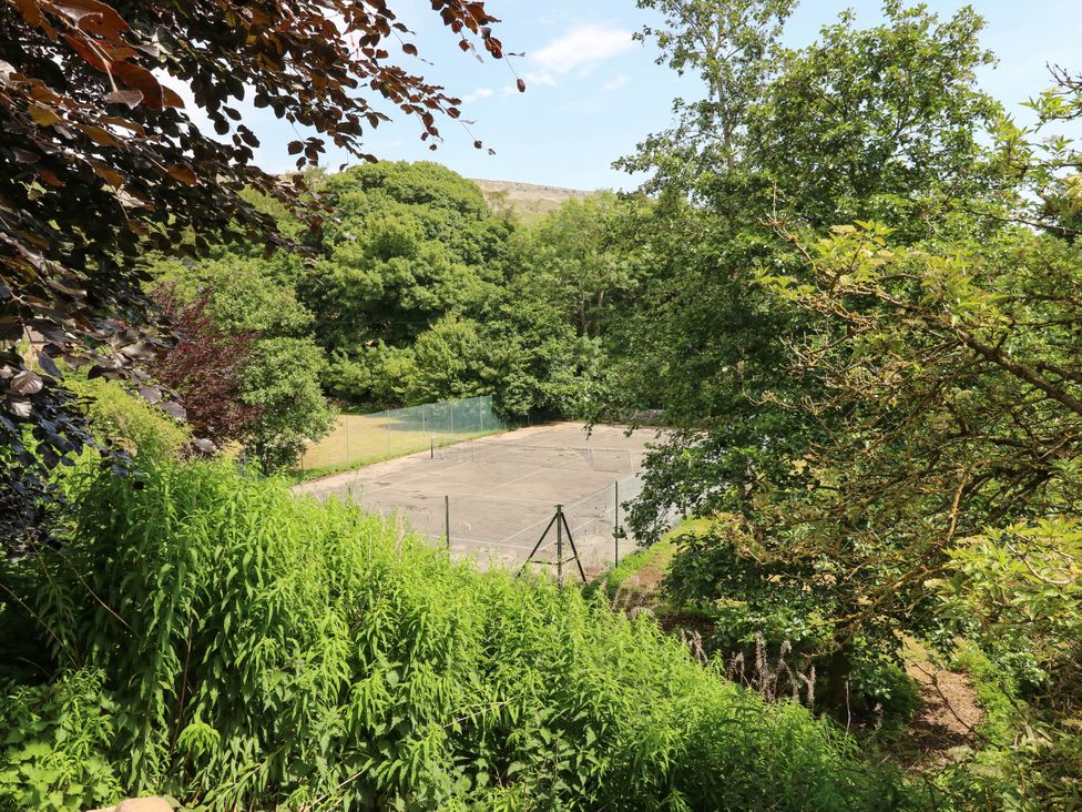An outdoor tennis court surrounded by trees at Kernot Cottage in Reeth