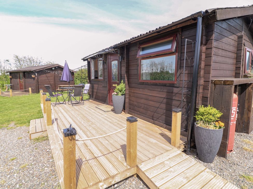 An outdoor area with a lodge and seating at Moorhen Lodge in Market Rasen