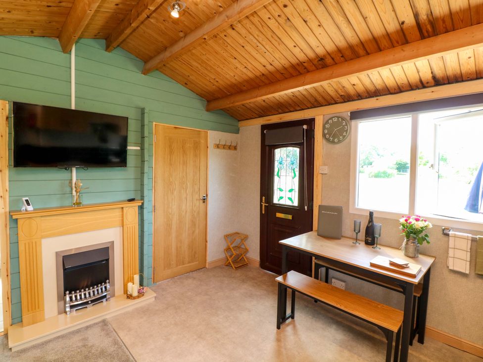 A living room with a television and a table at Moorhen Lodge in Market Rasen