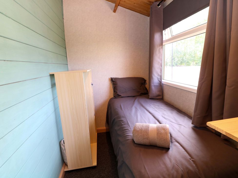 A bedroom with a bed and a shelf at Moorhen Lodge in Market Rasen