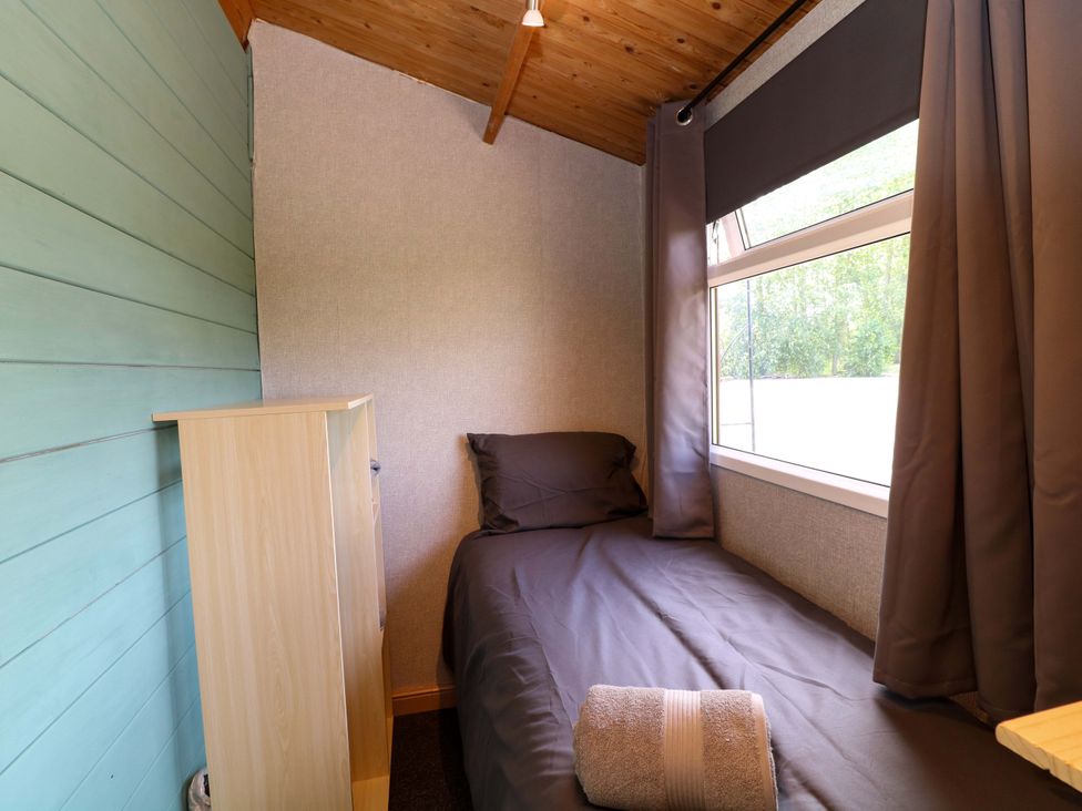 A bedroom with a bed and a shelf at Moorhen Lodge in Market Rasen