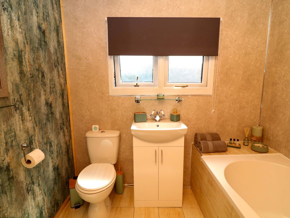 A bathroom with a toilet, sink, and bathtub at Moorhen Lodge, Market Rasen