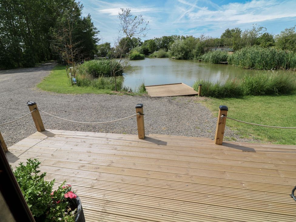 A view of a pond and wooden deck at Moorhen Lodge in Market Rasen