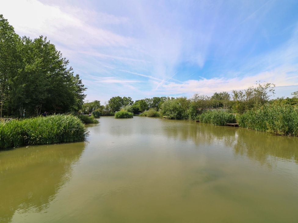 A body of water surrounded by grass and trees at Moorhen Lodge in Market Rasen