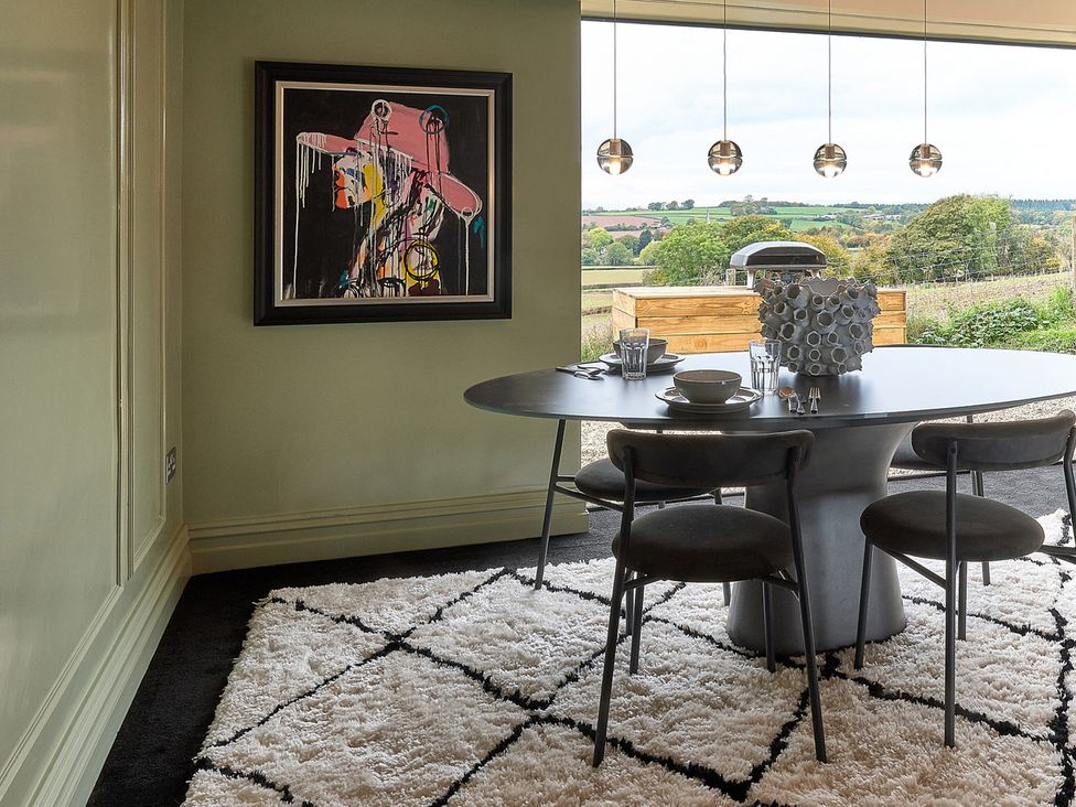 A dining room with a circular table and artwork at Providence Cottage Trellech