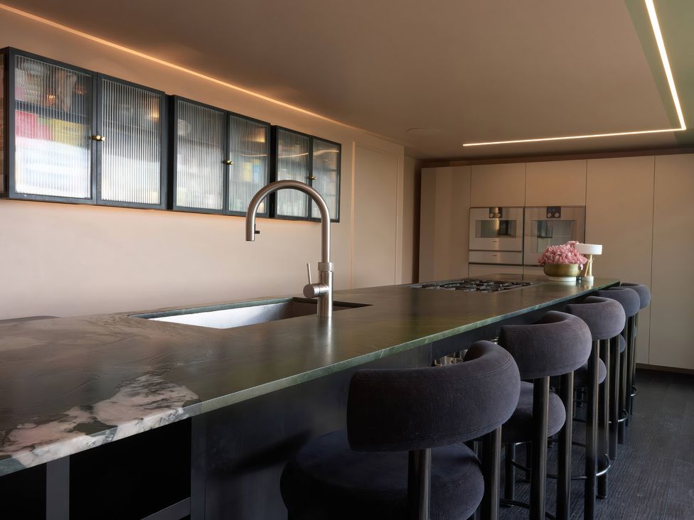 A kitchen with an island, sink, stools, and cabinets at Providence Cottage in Trellech