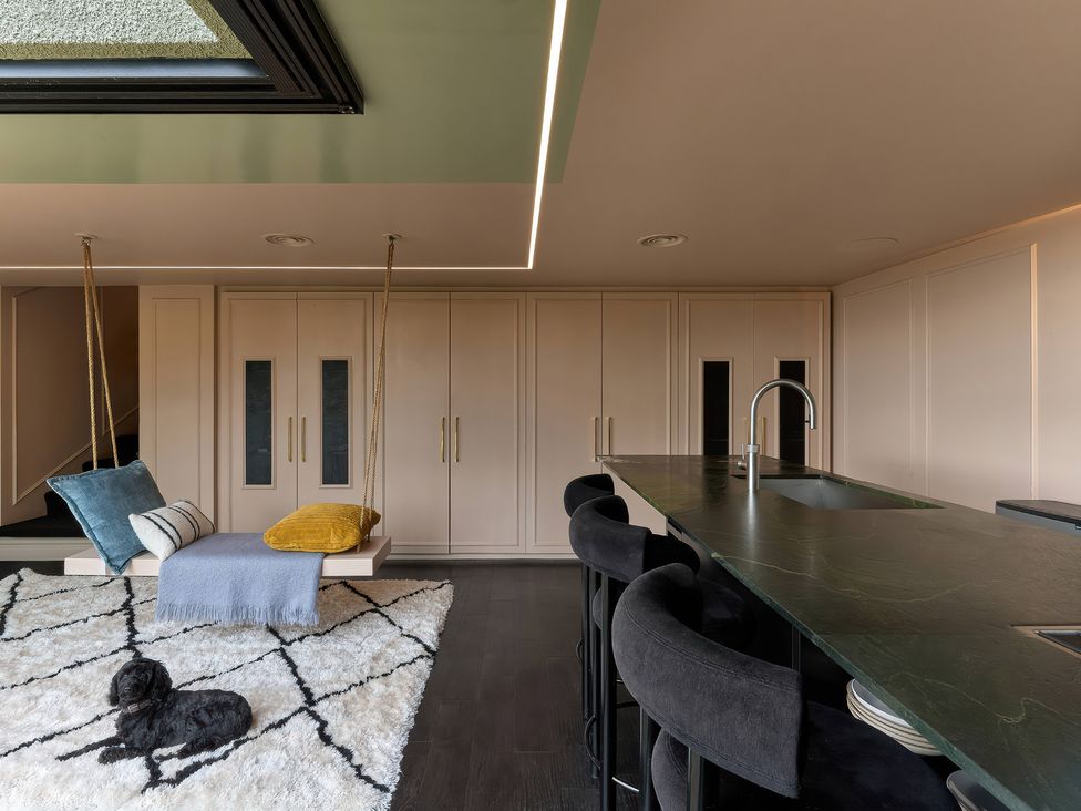 A kitchen with a swing seat and bar stools at Providence Cottage in Trellech