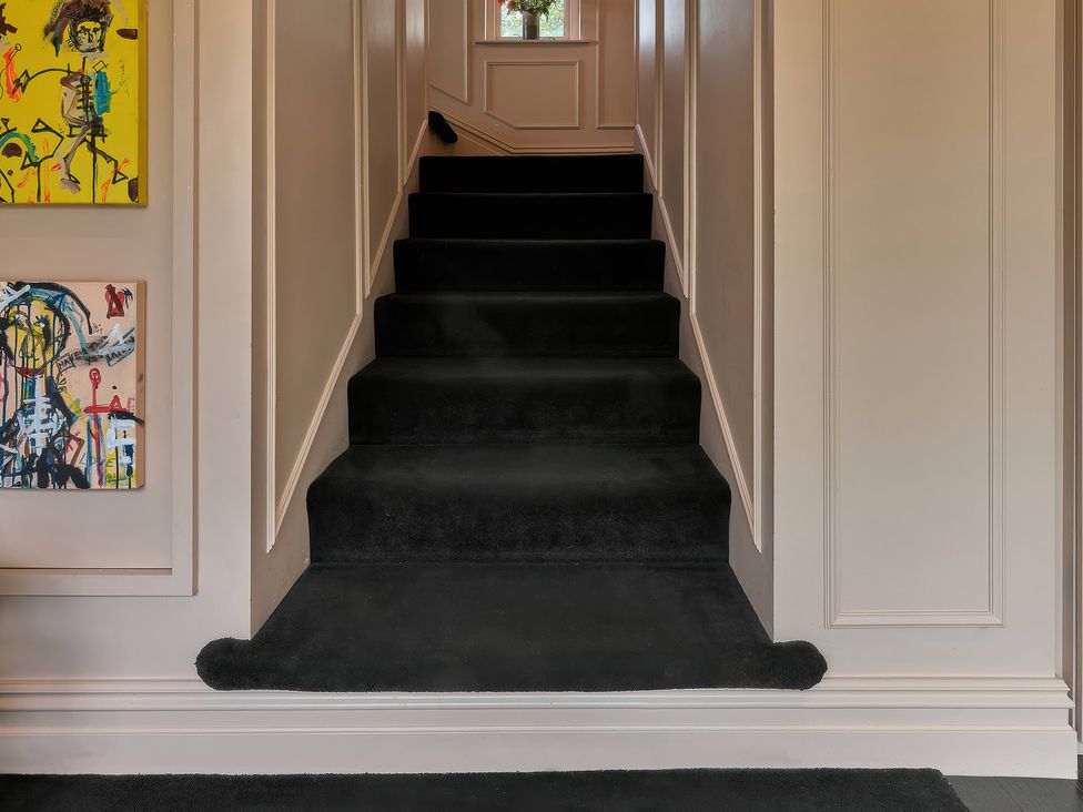 A staircase with artworks on the wall at Providence Cottage, Trellech
