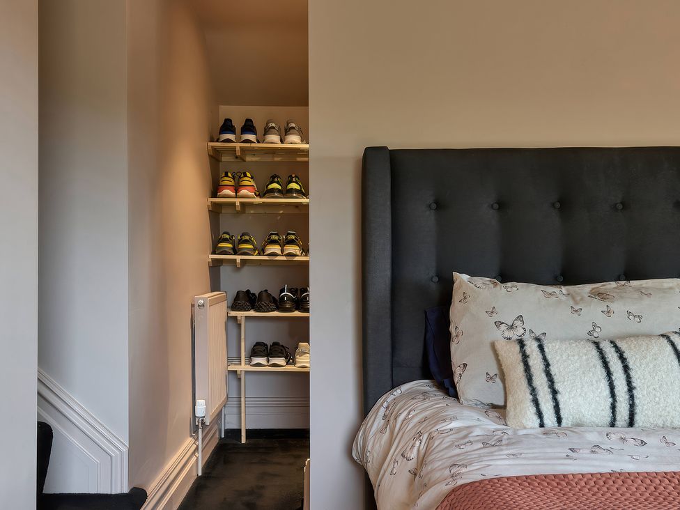 A bedroom with a bed and shoe storage at Providence Cottage in Trellech