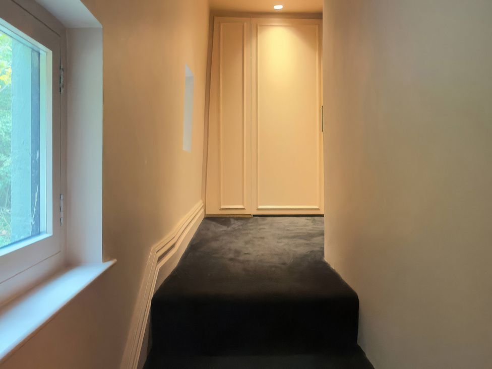 A staircase leading to a door in a hallway at Providence Cottage Trellech